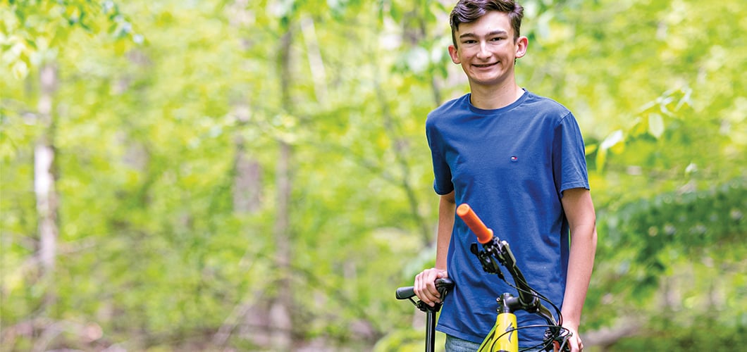 Teenager with a bike in front of a forest